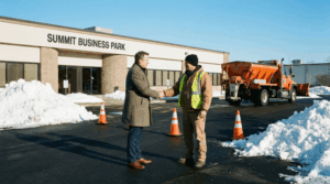 Business owner shaking hands with a snow removal contractor outside a plowed commercial property with clean walkways and snow piles